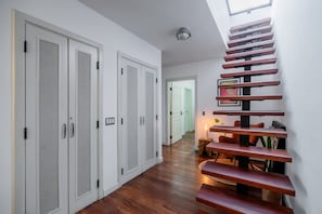 A modern interior with a wooden staircase, white doors with ventilation, and a wooden floor. - w* | Charming 2BR in Casco Antiguo (Panamá)
