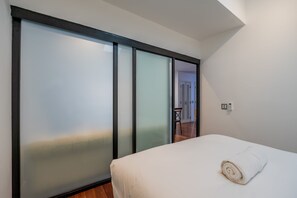 A bedroom with a bed, a towel, a sliding door, and a visible door leading to another room. - w* | Charming 2BR in Casco Antiguo (Panamá)