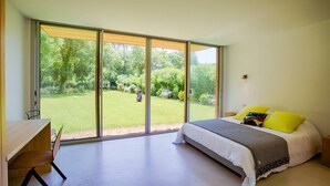 A bedroom with a large sliding glass door leading to a garden. - Villa Maupiti Avec Piscine Chauffée (HOSSEGOR)