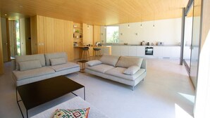 A modern living room with a sofa, a coffee table, and a kitchen area in the background. - Villa Maupiti Avec Piscine Chauffée (HOSSEGOR)