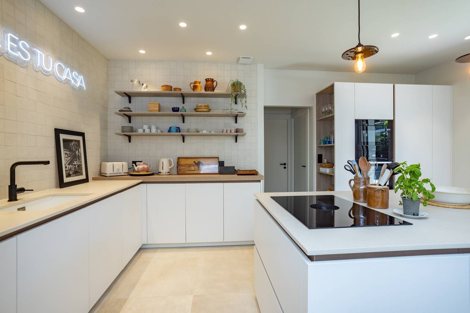 A modern kitchen with white cabinetry, a central island, and a hanging light fixture.