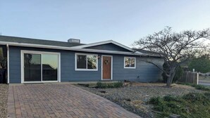 Ein Bungalow mit einer Ziegelterrasse, die zu einer Haustür führt.