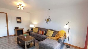 Ein Wohnzimmer mit einer Couch, einem Couchtisch, einer Stehlampe und einem Kamin.
