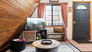 Een gezellige woonkamer met een televisie, een ronde salontafel en een bankje.