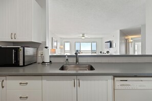 A kitchen with white cabinets, a microwave, a sink, and a dishwasher.