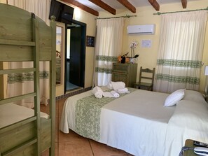 A neatly arranged bedroom with a bed, a wooden chair, a dresser, and an air conditioning unit. - Hotel Fiore di Maggio (Villasimius)