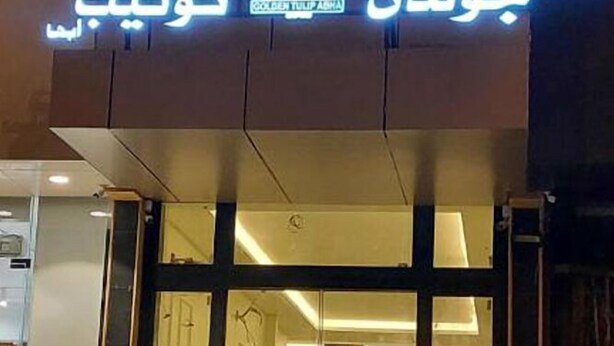 A hotel sign with Arabic text and a logo.