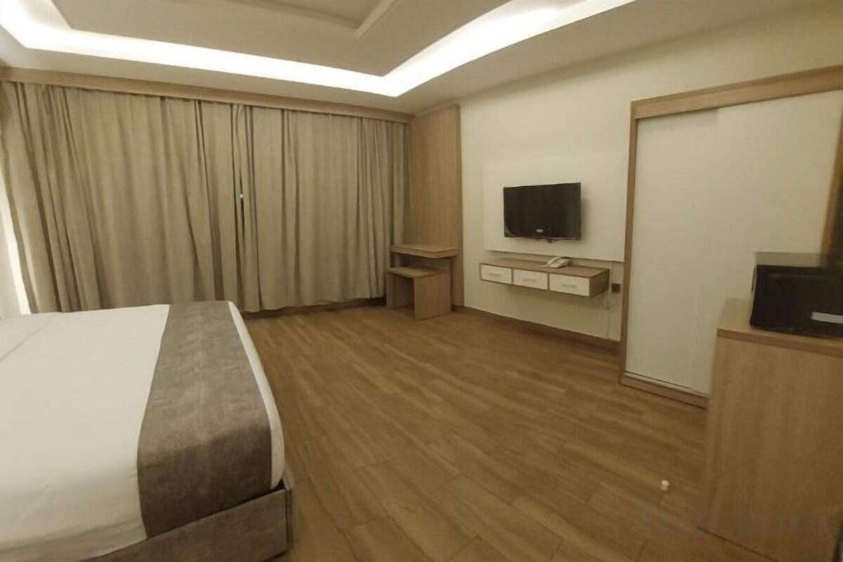 A hotel room with a bed, a television, a desk, and a wardrobe.