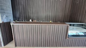 A reception desk with a wooden finish and a glass display case.