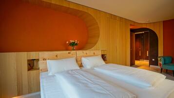 Una cama doble con sábanas blancas, cabecera de madera y un florero con flores.