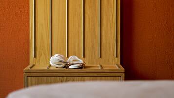 A wooden headboard with a towel and a pen on a bedside table against an orange wall.