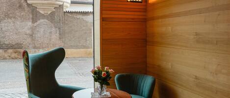 Una habitación con dos sillas y una mesa, techo de madera y vista a un edificio.