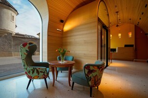Un interior moderno con paneles de madera, una mesa redonda de madera con sillas y un jarrón de flores.