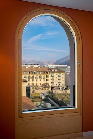 Une vue à travers une fenêtre à cadre en bois, avec un ciel dégagé et des montagnes lointaines.