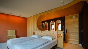 Un dormitorio moderno con cabecera de madera, cama con ropa de cama blanca y un armario de madera.