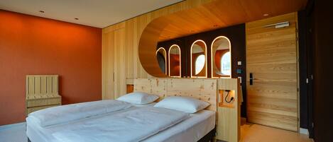Un dormitorio moderno con cabecera de madera, cama con ropa de cama blanca y un armario de madera.