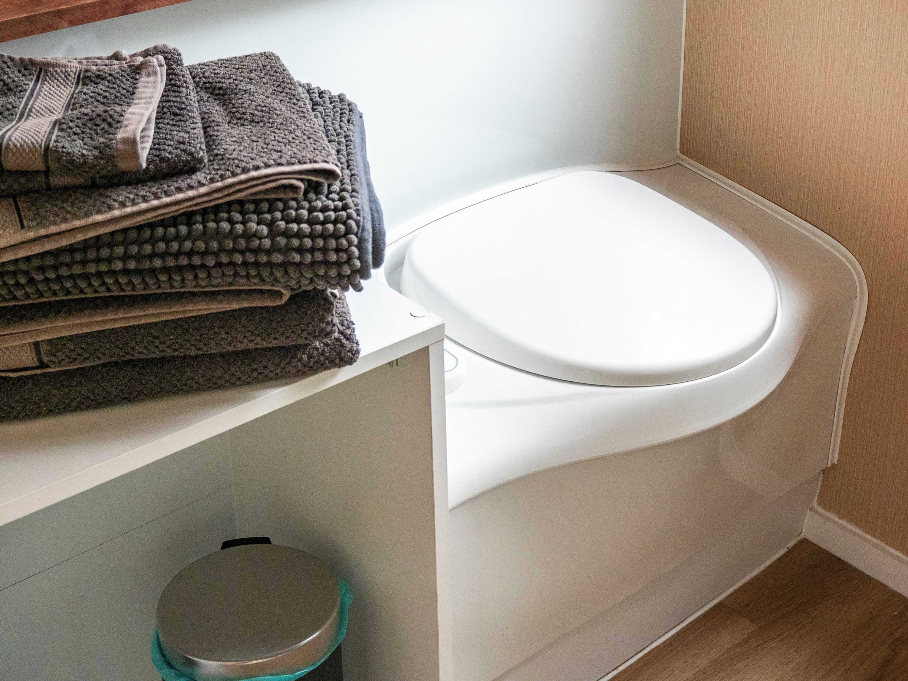 A bathroom with a toilet, a sink, and a trash bin.
