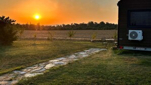 A wooden cabin with a clear view of the sunset, a paved path, and a field in the background. - Dolce Casa 1 by Tiny Away (Rigutino)