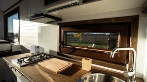 A compact kitchen with a gas stove, a sink, and a window overlooking a field. - Dolce Casa 1 by Tiny Away (Rigutino)