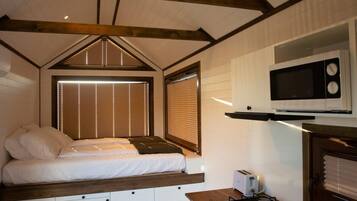 A compact bedroom with a bed, bedside tables, and a hanging light fixture.