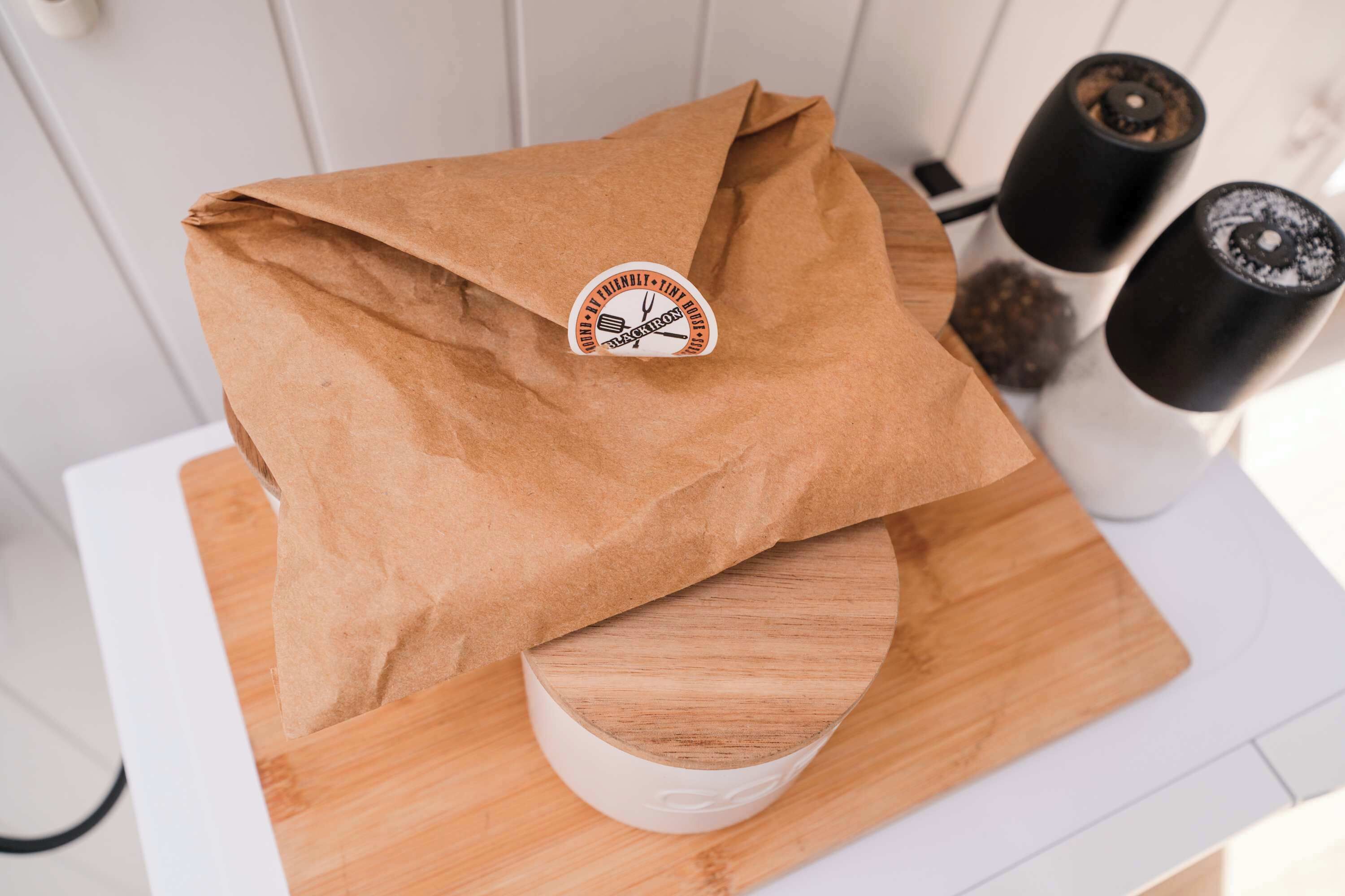 Un sac en papier brun avec un autocollant collé sur une planche à découper en bois.