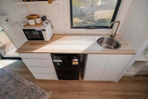 A compact kitchen with a microwave, sink, and dishwasher. - Echidna by Tiny Away (Andromache)