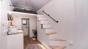 Um espaço interior compacto, com vários níveis, escada, cozinha compacta e área de refeições.