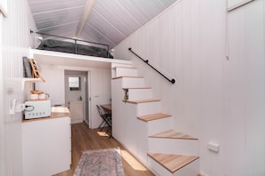 A compact, multi-level interior with a staircase, a kitchenette, and a dining area. - Echidna by Tiny Away (Andromache)