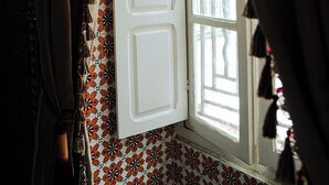 Une pièce avec une fenêtre, un papier peint à motifs et des rideaux.