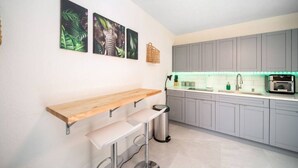 A modern kitchen with grey cabinets, a wooden countertop, a built-in oven, and a hanging basket.