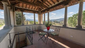 A covered patio with a table and chairs, overlooking a scenic landscape.
