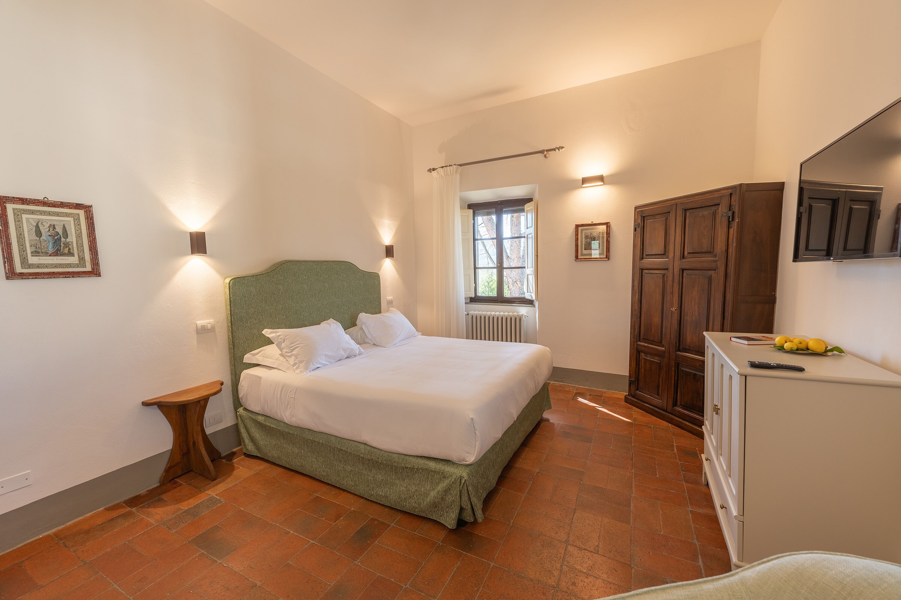 A bedroom with a bed, bedside table, wardrobe, and a window with curtains.