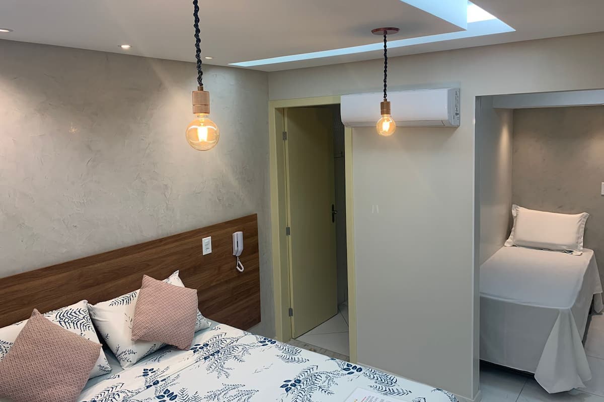 A bedroom with a bed, bedside tables, and a door leading to another room.