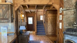 A wooden interior with a fireplace, a staircase, and a wooden bench. - Greer Pershing Cabin in the Meadow (Greer)
