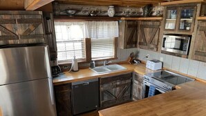 A kitchen with wooden cabinets, a stainless steel refrigerator, a microwave, and a sink. - Greer Pershing Cabin in the Meadow (Greer)