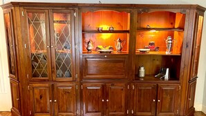 A wooden cabinet with multiple compartments, including glass doors and drawers, likely used for storage.