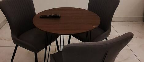A modern dining area with a round wooden table and four dark chairs.