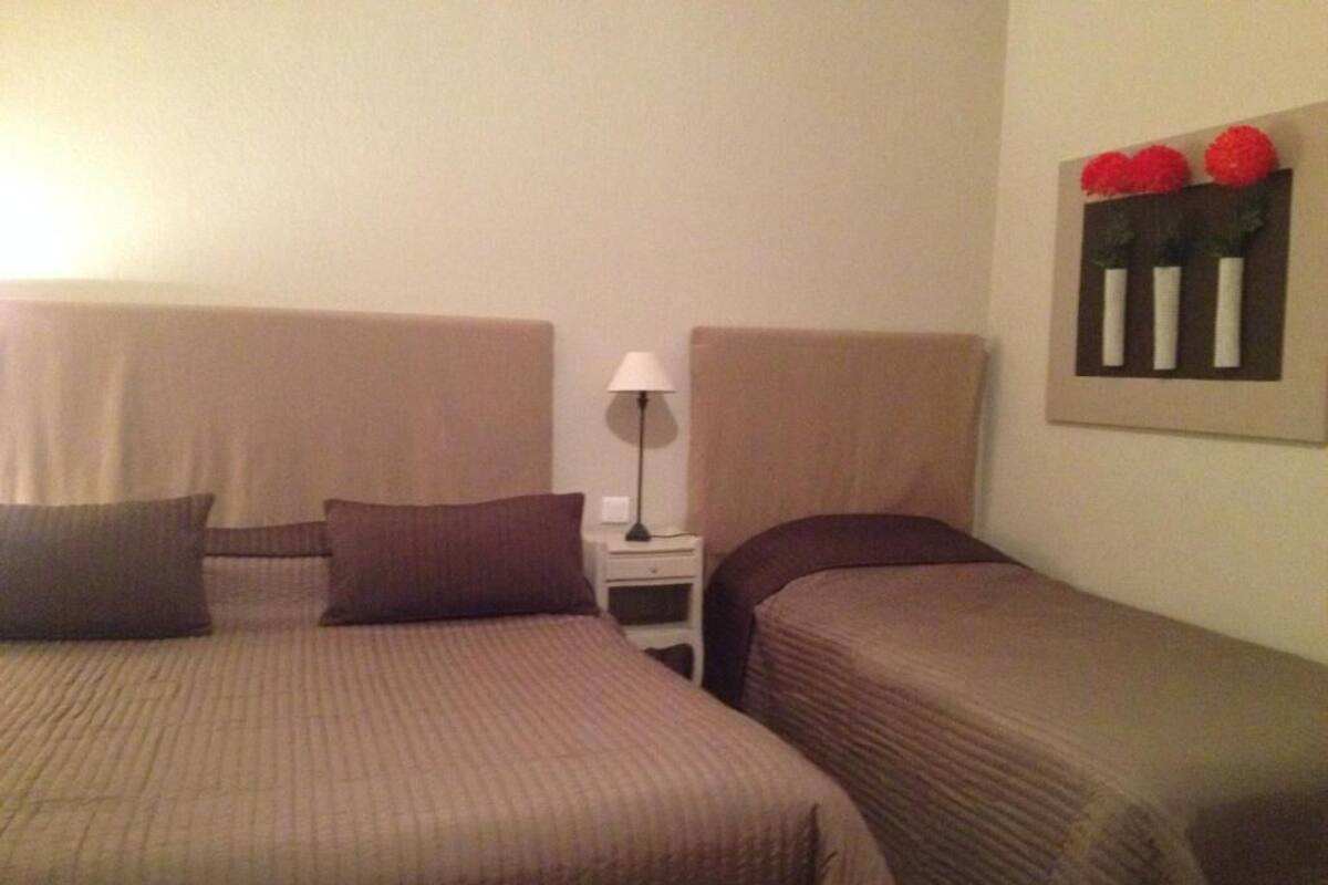 Une chambre d’hôtel avec deux lits, une table de chevet et une lampe.