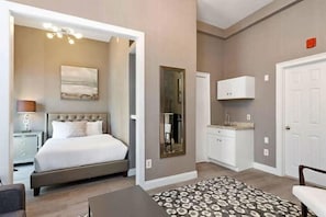 A bedroom with a bed, bedside table, lamp, and a mirror.