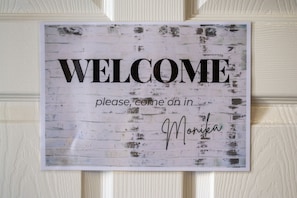 A welcome sign with the text "WELCOME please come in" and a signature.