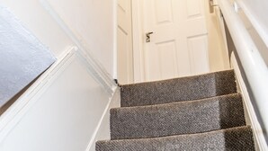 A staircase with carpeted steps leading to a white door at the top. - 2 bed house Sedley Street Liverpool (Liverpool)