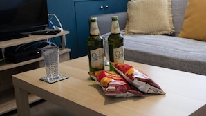 A living room with a TV, two bottles of beer, a glass, and a bag of snacks on a wooden table. - 2 bed house Sedley Street Liverpool (Liverpool)