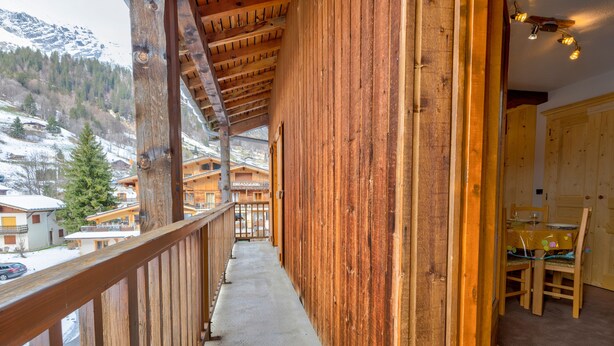 Ein Holzbalkon mit Blick auf verschneite Häuser und Berge.