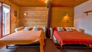 Eine Holzhütte mit zwei Betten, jeweils mit einer roten Decke und dekorativen Kissen.