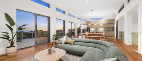 A modern interior with a curved sofa, a dining area, and a kitchen.