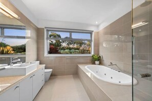 A modern bathroom with a large window, a bathtub, and a vanity with a sink. - Waterline Ocean Front Luxury  Bells Beach (Jan Juc)