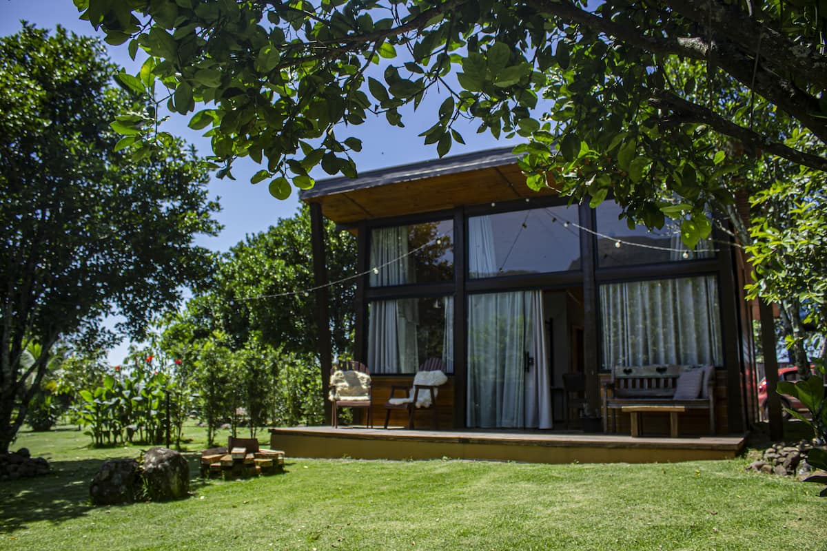 A modern house with a glass facade, a wooden deck, and outdoor furniture.
