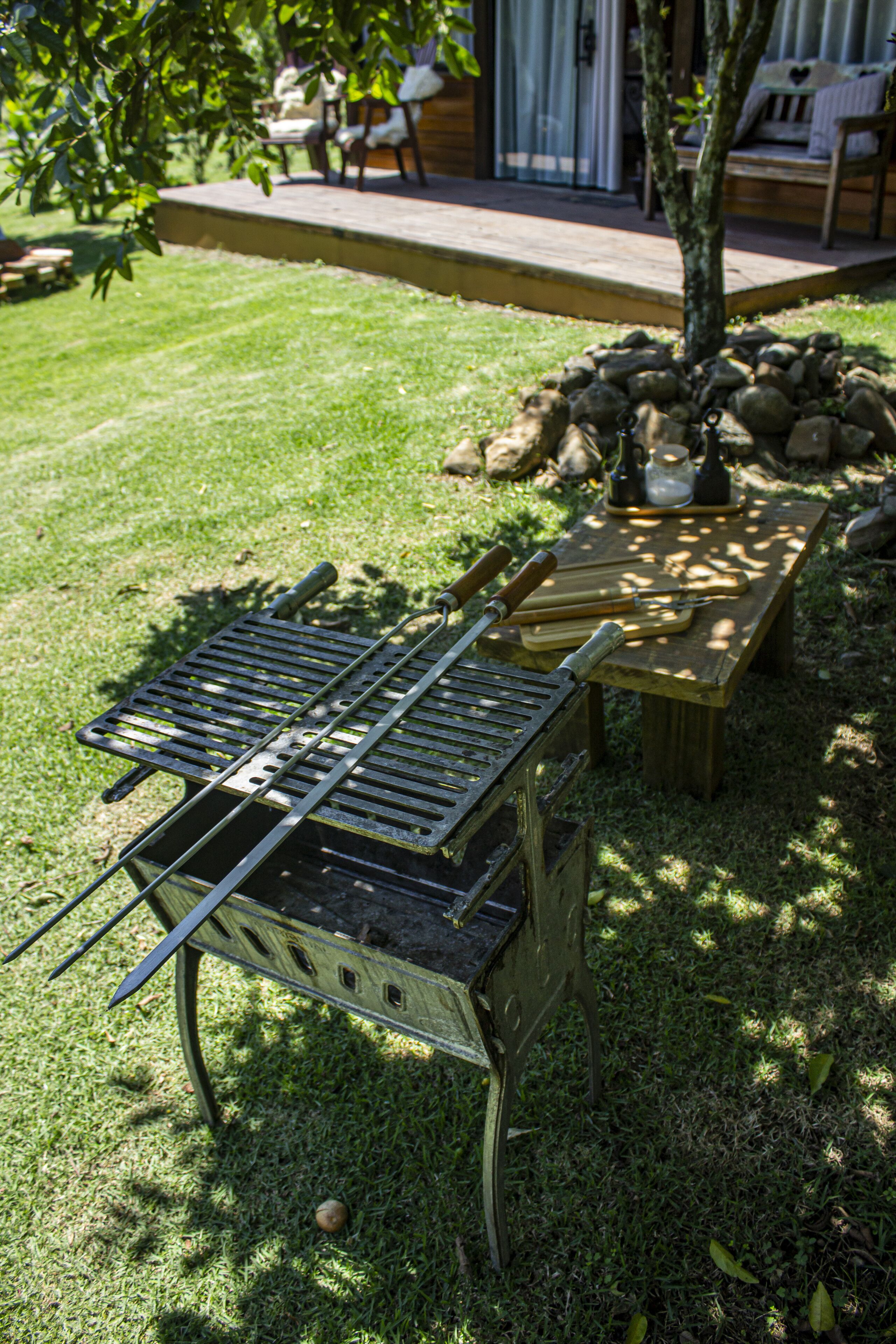 Patio con una parrilla metálica, una mesa de madera y un muro de piedra.