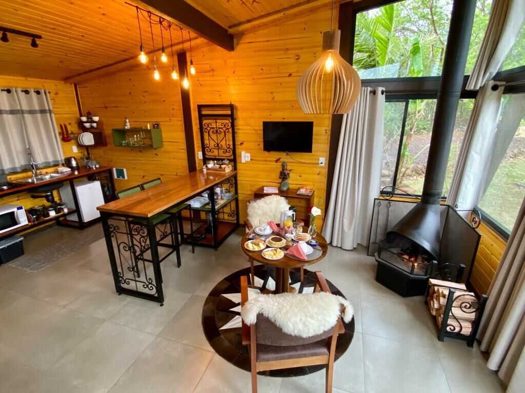 A cozy cabin interior with a dining area, kitchen, and a wood-burning stove.