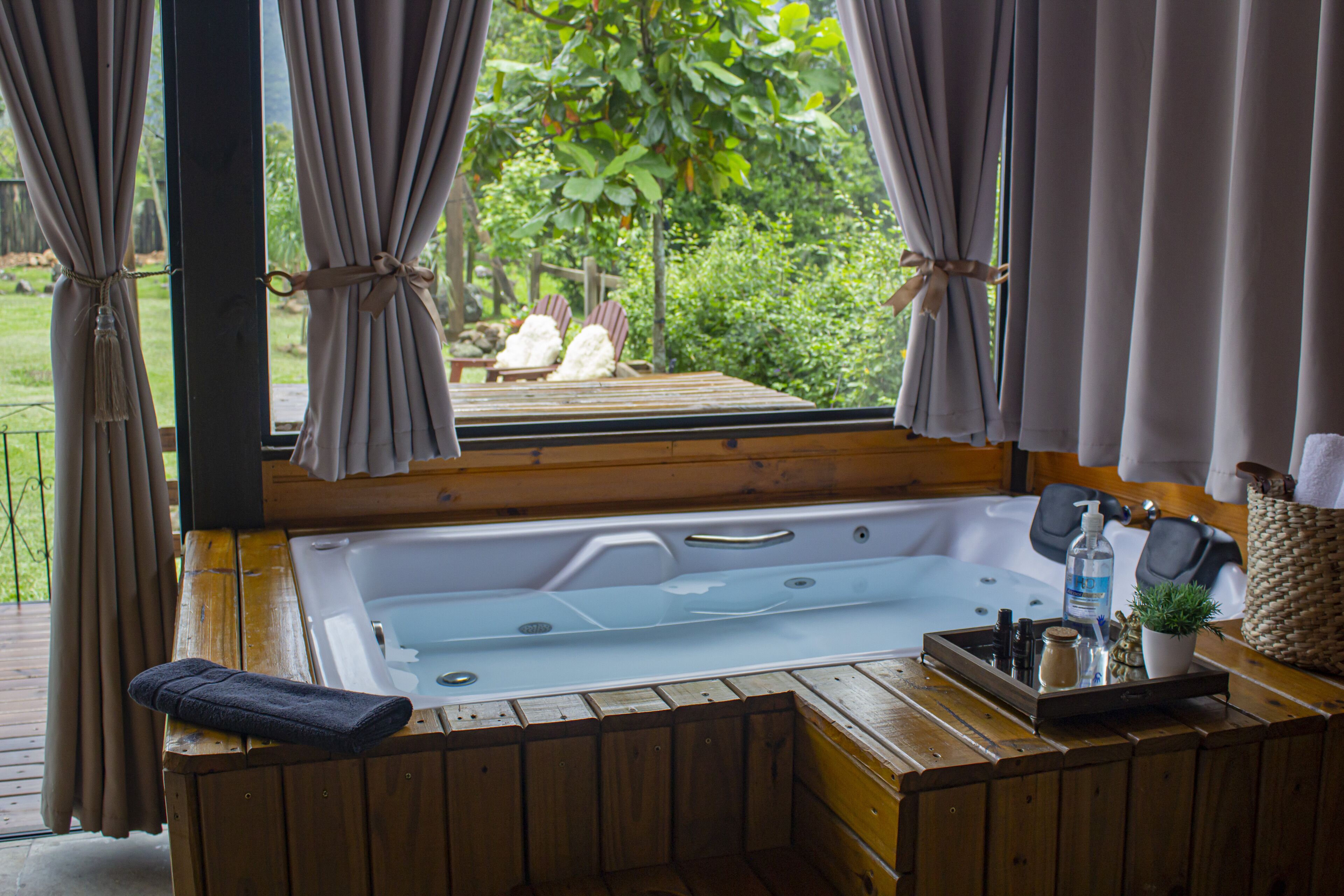 A wooden spa tub with a view of a garden.